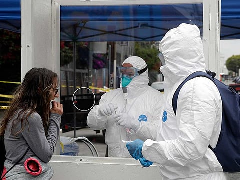 In this April 20, 2020, file photo, members of the Los Angeles Fire Department wear protective equipment as they conduct a COVID-19 test on a woman, left, in the Skid Row district in Los Angeles. California public health officials are now recommending health care workers and others in high risk settings who do not have symptoms be tested for the coronavirus.