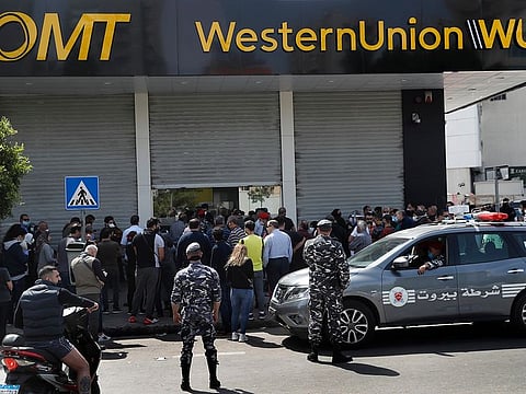 Lebanese citizens queue outside a Western Union shop to receive their money transfer in U.S. dollar currency, after the Central Bank circular issued this week, money transfer houses and banks are required to convert foreign currency transfers and cash withdrawals from foreign currency bank accounts to local currency at a market rate, in Beirut, Lebanon, Thursday, April 23, 2020. Lebanon's currency continued its downward spiral before the dollar on Thursday, reaching a new low amid financial turmoil in the crisis-hit country.