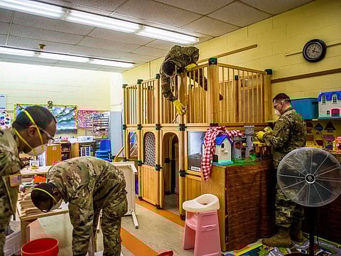 Members of the US state National Guard use a chlorine bleach solution to clean toys in a children's play room at the Jewish Community Center of Mid-Westchester in Scarsdale, N.Y., on Monday, March 16, 2020, to help prevent spreading the coronavirus. The concept of social distancing is now intimately familiar to almost everyone but as it first made its way through the federal bureaucracy in 2006 and 2007, it was viewed as impractical, unnecessary and politically infeasible.