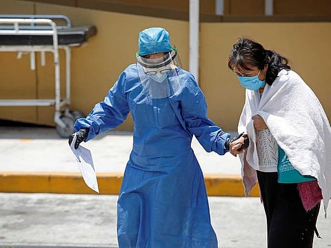 A healthcare worker wearing protective gear, accompanies a patient suffering from the coronavirus disease (COVID-19) to a triage station, at the Hospital General in Mexico City, Mexico April 23, 2020.