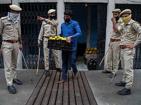 Indian security personnel seize fruits from a vendor who was selling them during nationwide lockdown in Gauhati, India, Thursday, April 23, 2020.