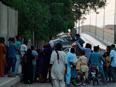 Men distribute food to people on the first day of the Islamic holy month of Ramadan in Karachi on April 25, 2020.