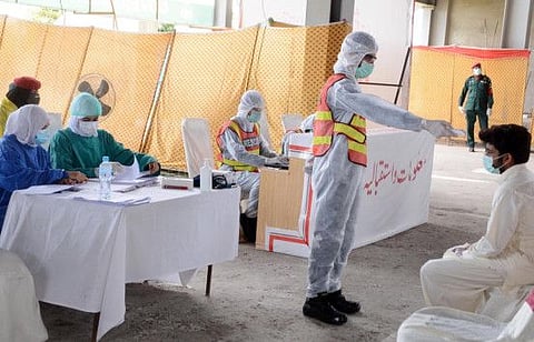 Woman doctors and health staff of Rescue 1122 checks the body temperature of a patient of coronavirus during a government-imposed nationwide lockdown.