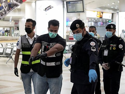 Police and civil aviation personnel wearing protective face masks work at the Kuwait Airport as the repatriation process of Kuwait citizens continues.