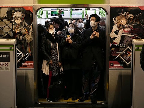 In this March 2, 2020, file photo, commuters wearing masks stand in a packed train at the Shinagawa Station in Tokyo. When the Japanese government declared an emergency to curb the spread of the coronavirus earlier April and asked people to work from home, crowds rushed to electronics stores.