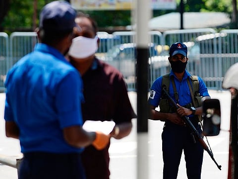 A Sri Lankan Navy personnel (R) wearing a facemask stands guard at a checkpoint during a government-imposed nationwide lockdown in Colombo on April 26, 2020.