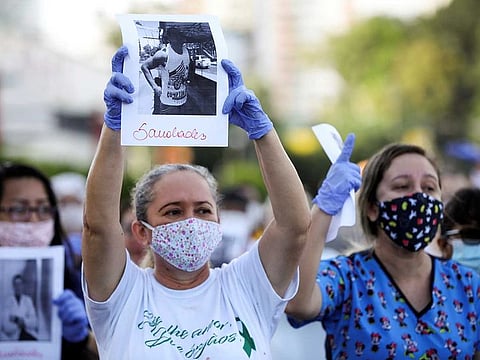 Healthcare workers wearing protective face masks pay tribute to their co-workers that have died from the coronavirus disease (COVID-19), amid the COVID-19 outbreak, and protest against the lack of personal protective equipment (PPE) in front of the 28 de Agosto hospital in Manaus, Brazil April 27, 2020. The signs read: "Miss you."