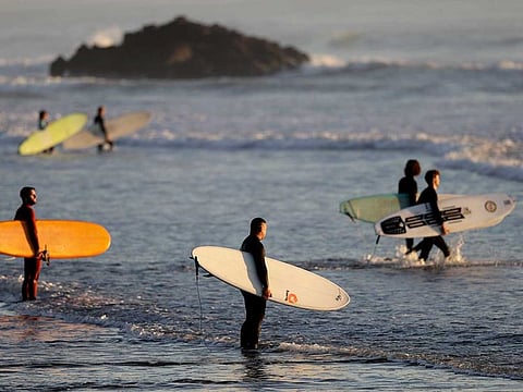 Surfers prepare to enter the water for a sunrise surf at Sumner Beach as level four COVID-19 restrictions are eased in Christchurch, New Zealand, Tuesday, April 28, 2020. New Zealand has asked its military to oversee border controls to stop COVID-19 infected patients from coming into the country.