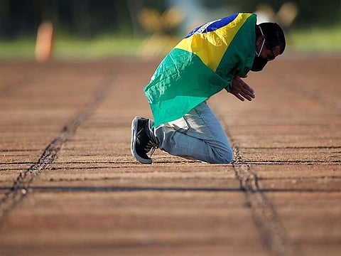 A man prays in front of the Alvorada Palace, amid the coronavirus disease (COVID-19) outbreak, in Brasilia, Brazil, April 28, 2020.