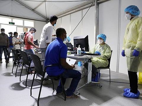 Medical staff wearing protective equipment intake patients to be tested at a clinic in UAE.