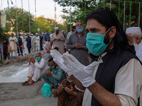 People pray ahead of Iftar at a food distribution point during Ramadan during a government-imposed nationwide lockdown to help contain the spread of the coronavirus, in Islamabad, Pakistan, Thursday, April 30, 2020.