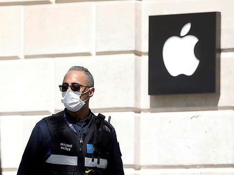 A policeman wearing a protective face mask walks past an Apple store