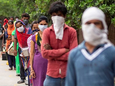FILE PHOTO: People wait to receive free food at an industrial area, during an extended nationwide lockdown to slow the spread of coronavirus disease (COVID-19) in New Delhi, India, April 23, 2020.