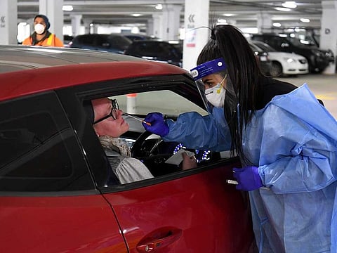 Medical staff perform a test for the COVID-19 coronavirus on a driver at a drive-through testing site in a Melbourne carpark on May 1, 2020. Australia will consider early easing of coronavirus restrictions next week, officials announced on May 1 as the number of local cases dwindled and the economic impact of the crisis fell into painful relief.