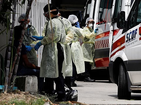 Medical personnel checks a temperature of a migrant worker at a factory-converted dormitory, in Singapore.