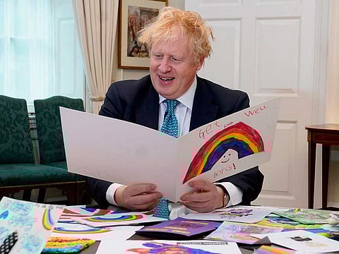 Britain's Prime Minister Boris Johnson displaying his Get Well Soon cards sent in by children while he was ill with the novel coronavirus, at his office in 10 Downing Street, central London on April 28, 2020.