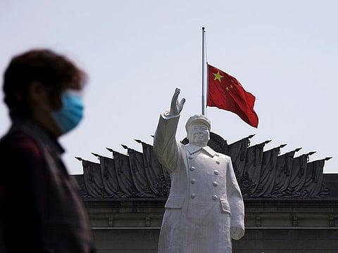 The Chinese national flag flies at half-mast behind a statue of late Chinese chairman Mao Zedong in Wuhan, Hubei province, as China holds a national mourning for those who died of the coronavirus disease (COVID-19), on the Qingming tomb-sweeping festival, April 4, 2020.