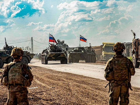 US soldiers stand along a road across from Russian military armoured personnel carriers (APCs), near the village of Tannuriyah in the countryside east of Qamishli in Syria's northeastern Hasakah province on May 2, 2020.