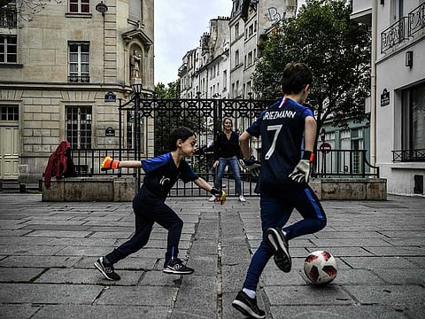 A woman and her children play football on a deserted square in Paris on May 4, 2020, on the 49th day of a lockdown in France aimed at curbing the spread of COVID-19, caused by the novel coronavirus.