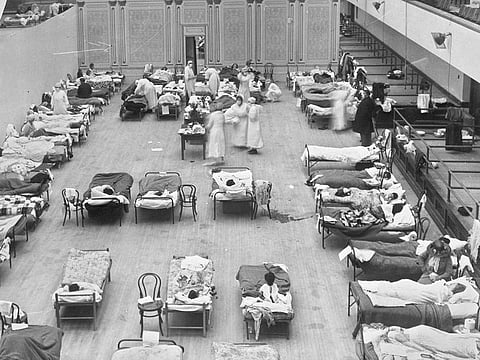 In this 1918 file photo made available by the Library of Congress, volunteer nurses from the American Red Cross tend to influenza patients in the Oakland Municipal Auditorium, used as a temporary hospital.