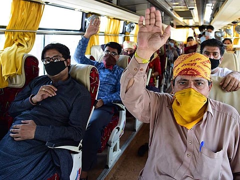 Pakistani nationals stranded in India wave sitting in a bus that will take them to the border, at the Integrated Check Post (ICP) at the India-Pakistan Wagah-Attari border, about 35km from Amritsar, India, Tuesday, May 5, 2020.