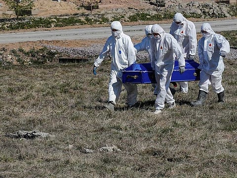 Grave diggers wearing personal protective equipment (PPE) carry a coffin while burying a coronavirus disease (COVID-19) victim in the special purpose section of a graveyard on the outskirts of Saint Petersburg, Russia May 5, 2020.