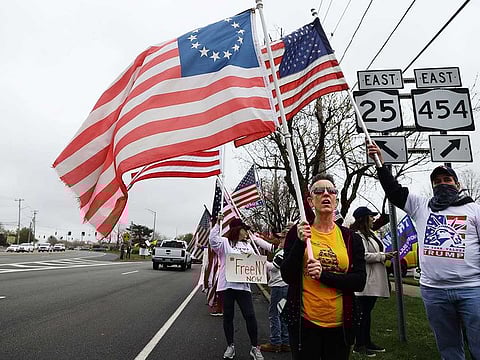Protesters hold signs during the Re-Open America rally on May 01, 2020 in Commack, New York. New York State Governor Andrew Cuomo has stated that he will consider easing shut-down requirements in regions of the state beginning May 15.