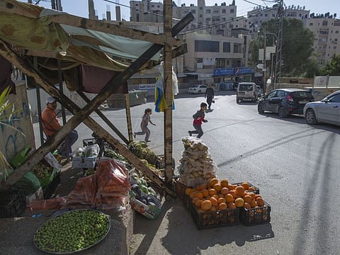 In this Tuesday, April 28, 2020 photo, a Palestinian vendor displays his vegetables in the street as the main vegetable market remains closed, part of lockdown and quarantine measures to protect residents from the coronavirus, in the West Bank village of Kufr Aqab. As the coronavirus pandemic gathered strength in April, community leaders in Kufr Aqab, a Palestinian neighbourhood on the outskirts of occupied Jerusalem, tried to impose lockdown and quarantine measures to protect residents.