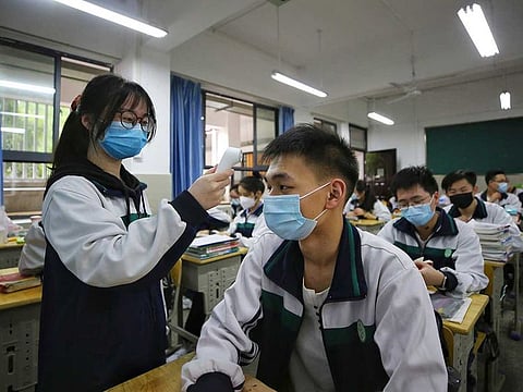 A female student wearing a protective face mask to help curb the spread of the new coronavirus checks temperature of her classmates at a high school in Wuhan in central China's Hubei province, Wednesday, May 6, 2020. Senior students returned to classes on Wednesday in the central Chinese city of Wuhan, the epicentre of the coronavirus pandemic, after no new cases or deaths were reported from the outbreak that had prompted a 76-day quarantine in the city of 11 million.