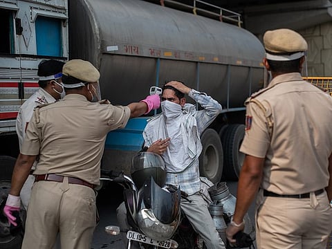 An Indian policeman uses a thermometer to check a commuter entering New Delhi from the neighboring state of Uttar Pradesh on Tuesday, April 28, 2020.