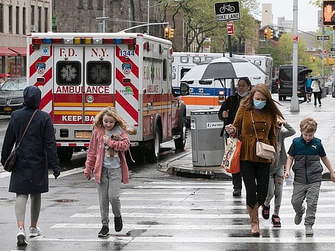 People walk by ambulances parked outside NewYork–Presbyterian Brooklyn Methodist Hospital, Wednesday, May 6, 2020 in New York during the coronavirus pandemic.