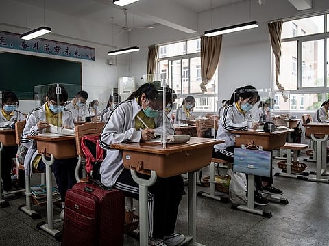 High school senior students study with plastic partitions in a classroom in Wuhan in China's central Hubei province on May 6, 2020.