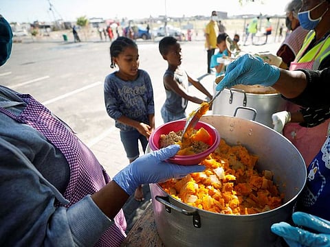 Children queue for food at a school feeding scheme during a nationwide lockdown aimed at limiting the spread of the coronavirus disease (COVID-19) in Blue Downs township near Cape Town, South Africa, May 4, 2020.