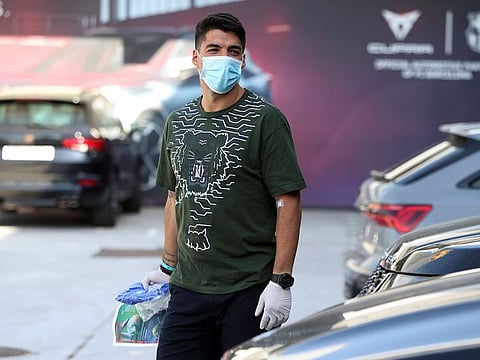 Barcelona's Luis Suarez walks wearing a protective face mask at the club's training ground