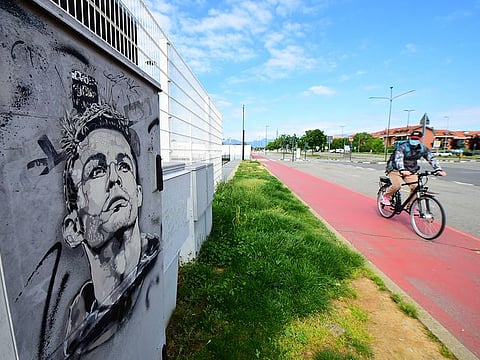 A man wearing a protective face mask cycles past a mural of Juventus' Cristiano Ronaldo outside of Juventus' Allianz Stadium.