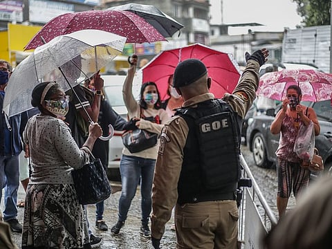A member of the Special Operations Group (GOE) police force speaks with pedestrians at a checkpoint in the Campo Grande neighborhood of Rio de Janeiro, Brazil, on Thursday, May 7, 2020.