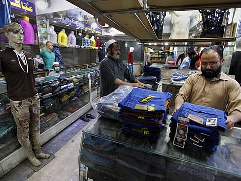 Shopkeepers adjust garments at a market after government lifting the weeks-long lockdown, in Rawalpindi, Pakistan.