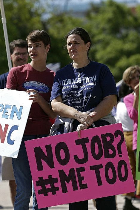 In Raleigh, N.C. a woman holds a no job sign during a rally near the General Assembly.
