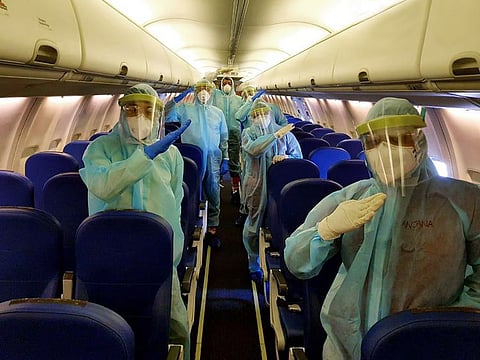 United Arab Emirates, May 07 (ANI): Cabin Crew members wear PPE kit gesture as Air India Express flight landed in Abu Dhabi on Thursday. (ANI Photo)