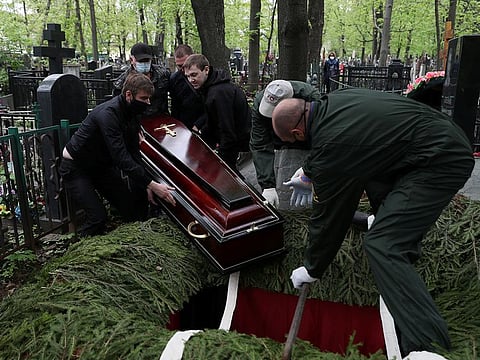 Funeral service workers lower the coffin of Orthodox deacon Andrei Molchanov, 54, who died after contracting the COVID-19, at a cemetery in Moscow.