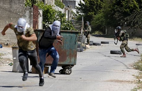 Palestinian demonstrators duck for cover as Israeli soldiers come charging down in the village of Kfar Qaddum in the Israeli-occupied West Bank