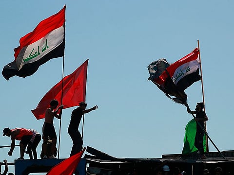 Anti-government protesters sit-in on barriers set up by security forces to close the Jumhuriyah bridge leading to the Green Zone government areas during ongoing protests, in Baghdad, Iraq, Sunday, May 10, 2020.