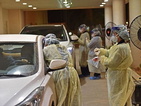 Health workers perform a nose swab test during a drive through coronavirus test campaign held in Diriyah hospital in the Saudi capital Riyadh on May 7, 2020 amid the COVID-19 pandemic. / AFP / FAYEZ NURELDINE