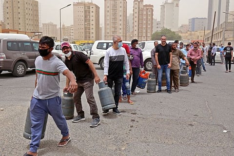 Paople queue in front of a shop to refill their gas cylinders in Kuwait City on May 10, 2020, a day after Kuwaiti authorities announced a 20-day total lockdown due to the COVID-19 pandemic. The lockdown will be implemented from May 10 to 30.