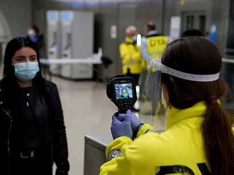 A member of the voluntary ambulance service organisation DYA (Detente y Ayuda) uses a thermal imaging camera to take the temperature of a train passenge in Bilbao, Spain.
