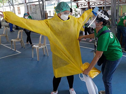A health worker puts on a protective suit as they conduct mass testing for COVID-19 in Manila, Philippines on Friday, May 8, 2020. AP