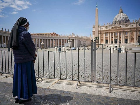 A nun waits for Pope Francis to deliver his blessing from the window of his studio overlooking an empty St. Peter's Square, due to anti-coronavirus lockdown measures, at the Vatican, Sunday, May 10, 2020.