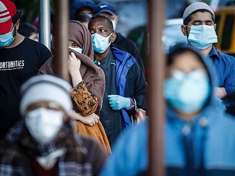 People wearing masks wait in line for food donations Wednesday, May 13, 2020, in the Brooklyn borough of New York, during the coronavirus pandemic.