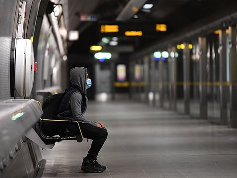A commuter wearing a face mask as a precautionary measure against COVID-19 waits to board a TfL (Transport for London) Jubilee Line underground train at Waterloo station in central London on May 13, 2020.