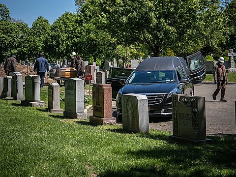 Cemetery workers prepare to bury a casket from McLaughlin & Sons funeral home, without any family present because of coronavirus restrictions at Holy Cross Cemetery in the Brooklyn borough of New York